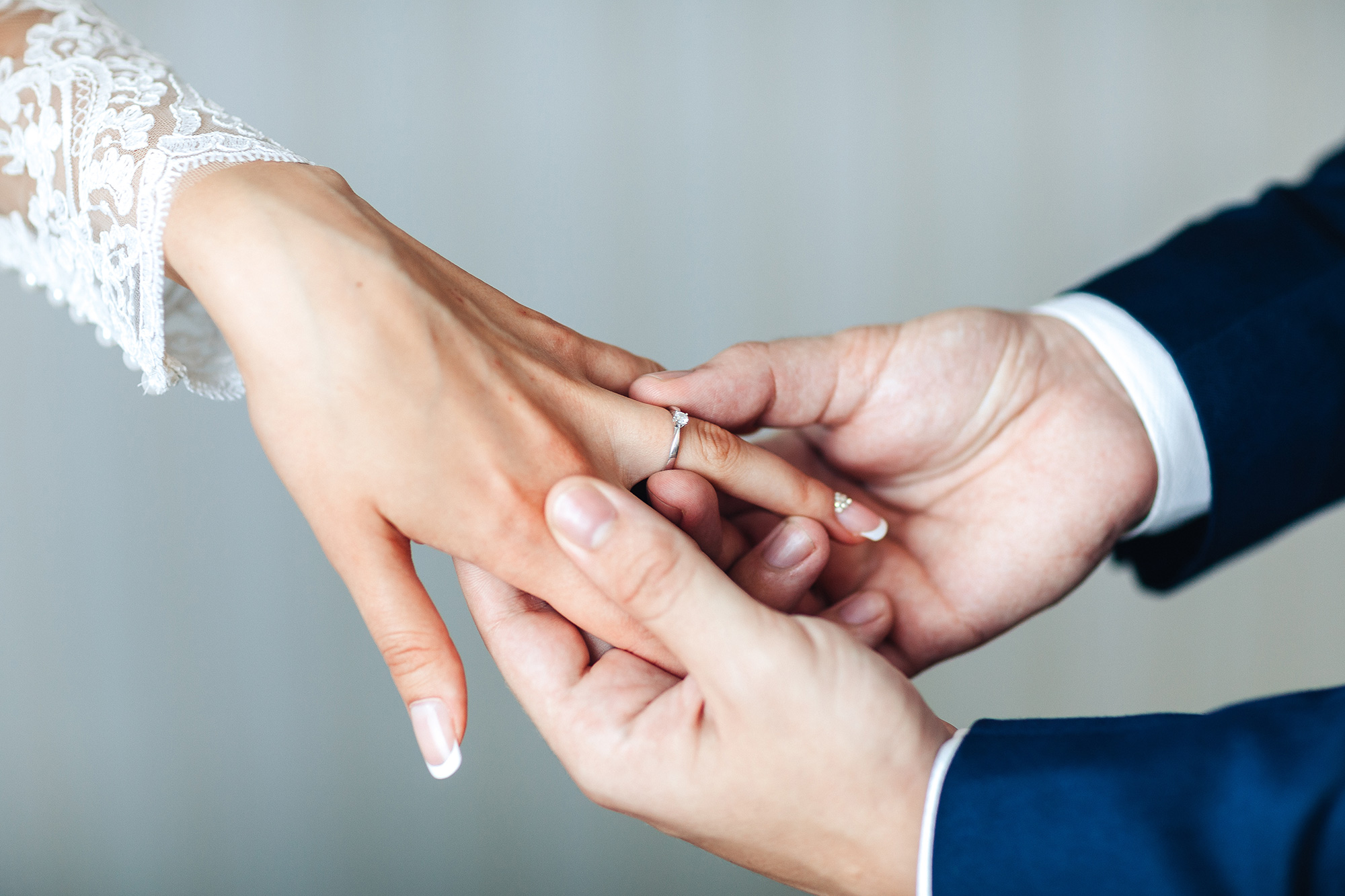 Top-down view of a pair of hands putting a wedding ring on another person’s hand